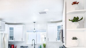 Eine moderne Küche mit weißen Schränken, einem Edelstahlkühlschrank, einer Spüle und einem Fenster.