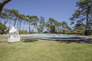 A swimming pool with a white sculpture in the foreground, surrounded by trees and a clear sky. - Liiiving in Ofir - Seaside Pool Bungalow (Fão)