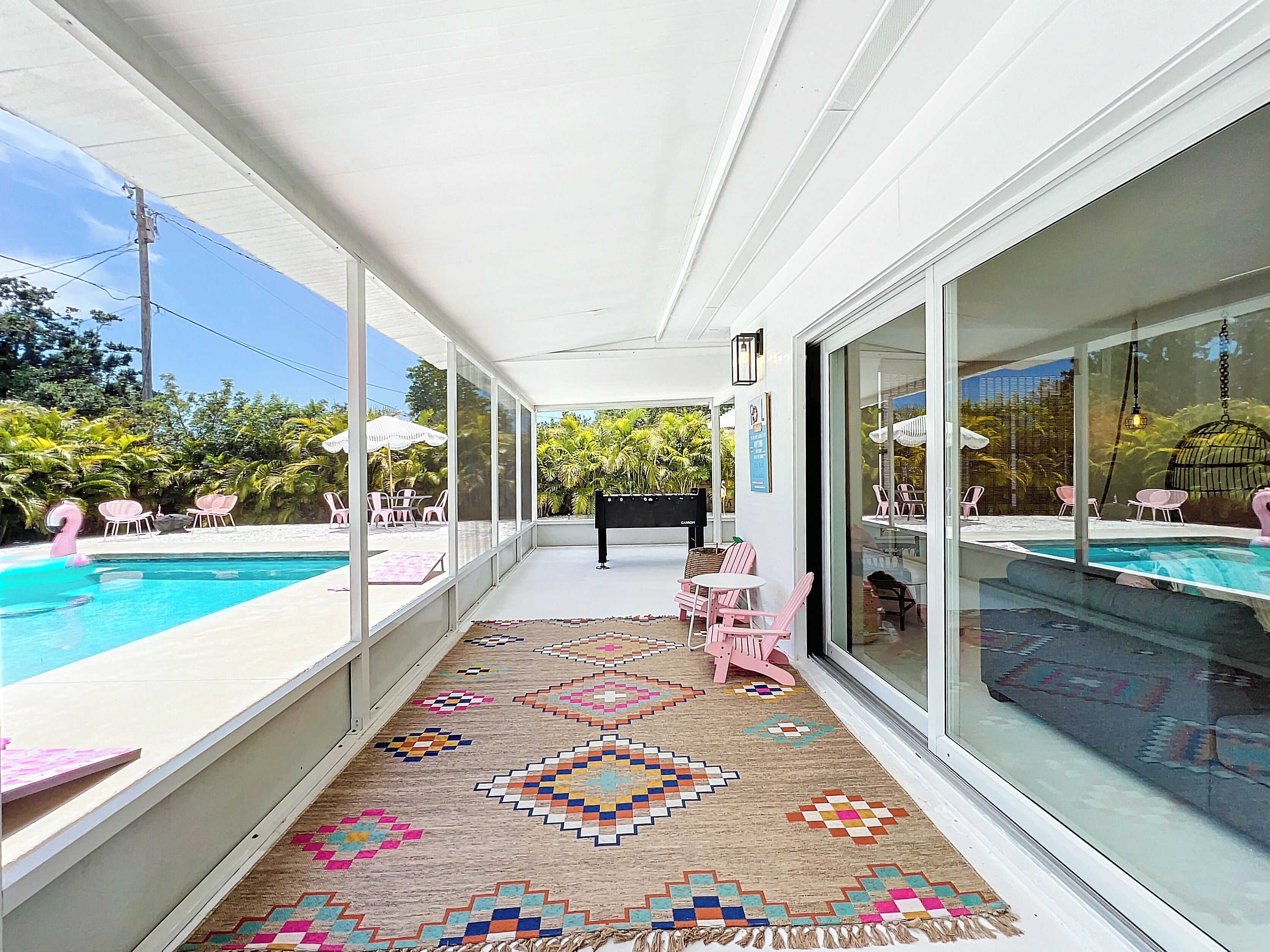 A covered patio with a pool, glass walls, and outdoor seating.