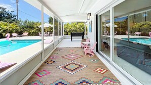 Une terrasse couverte avec une piscine, des murs en verre et des sièges d’extérieur.