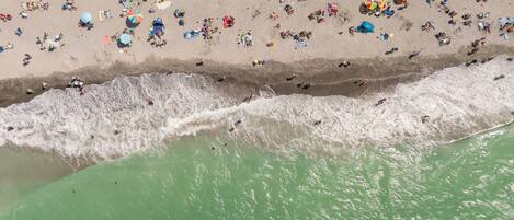 Vista aérea de una playa con gente, sombrillas y sillas de playa.