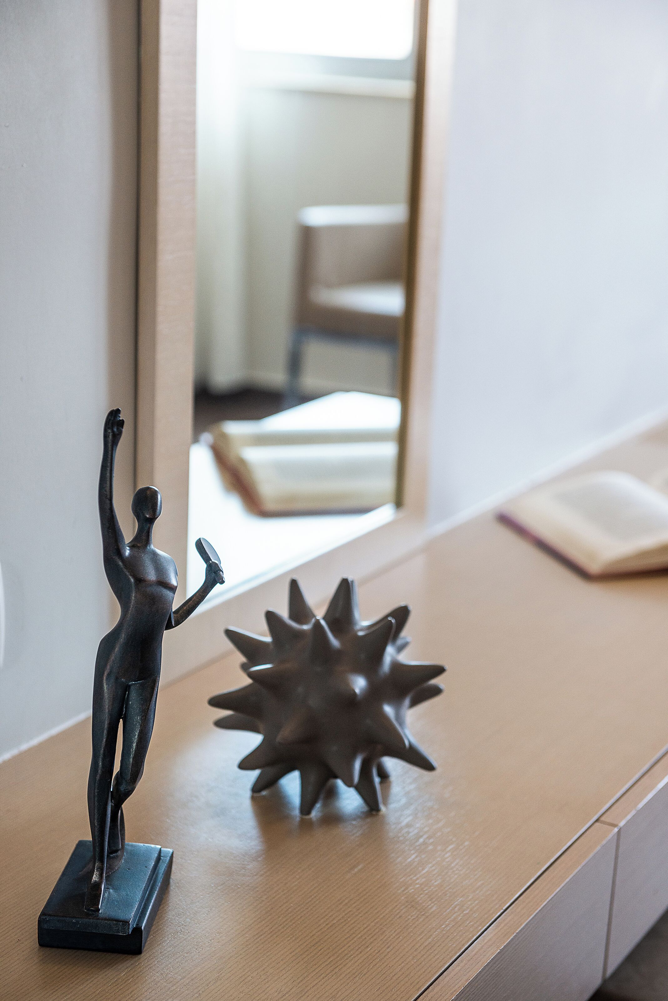 Un escritorio de madera con una estatua y un objeto decorativo.