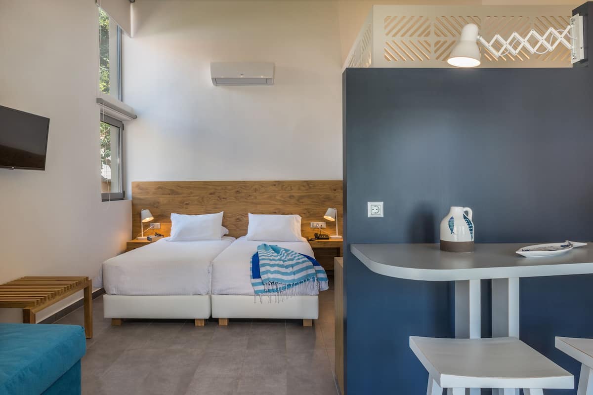 A bedroom with a bed, bedside tables, a TV, a window, and a desk with a chair.