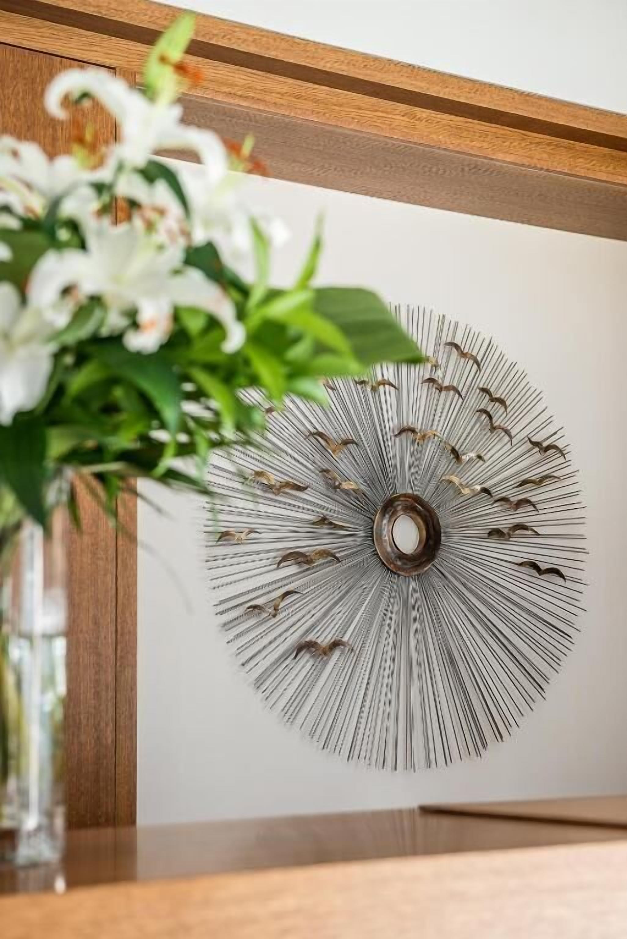 A wall-mounted decorative piece with a central circular element surrounded by radiating lines.