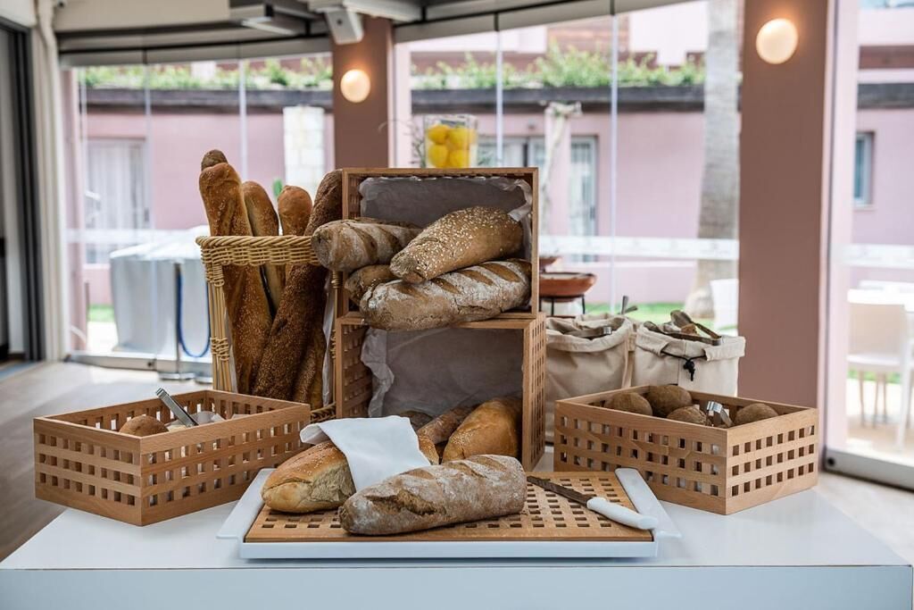 Une variété de pains est exposée sur une table dans une pièce bien éclairée, dotée de grandes fenêtres.
