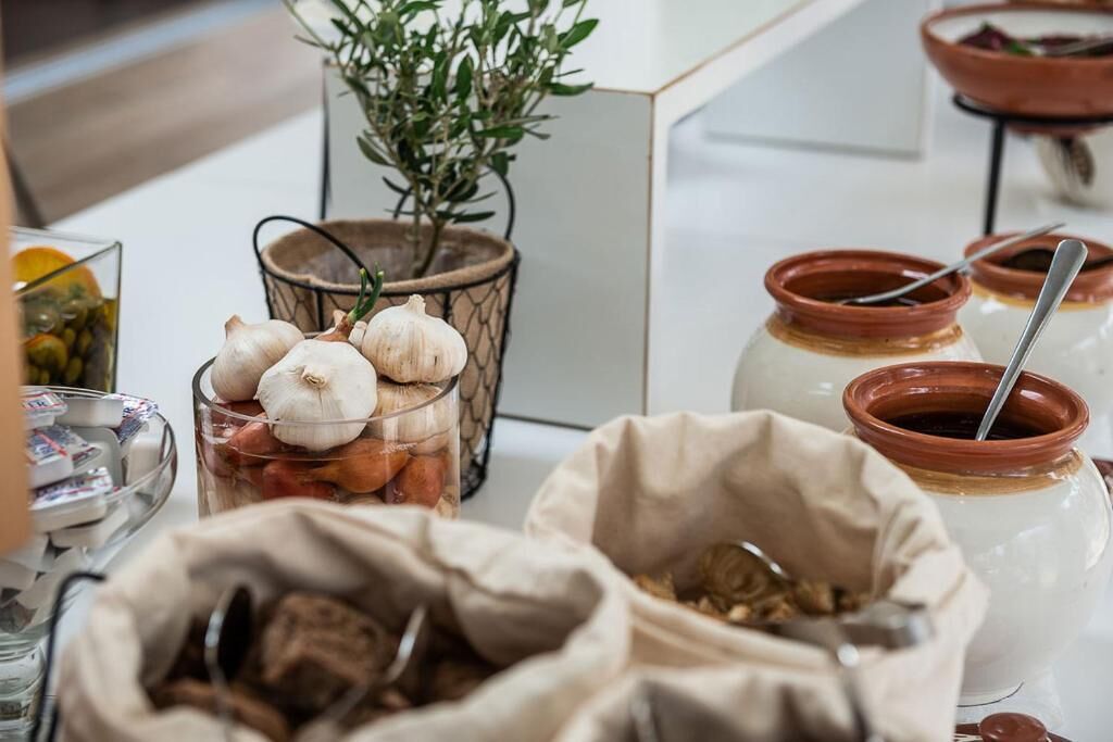 A kitchen counter with jars of spices, a bowl of garlic, and a potted plant.