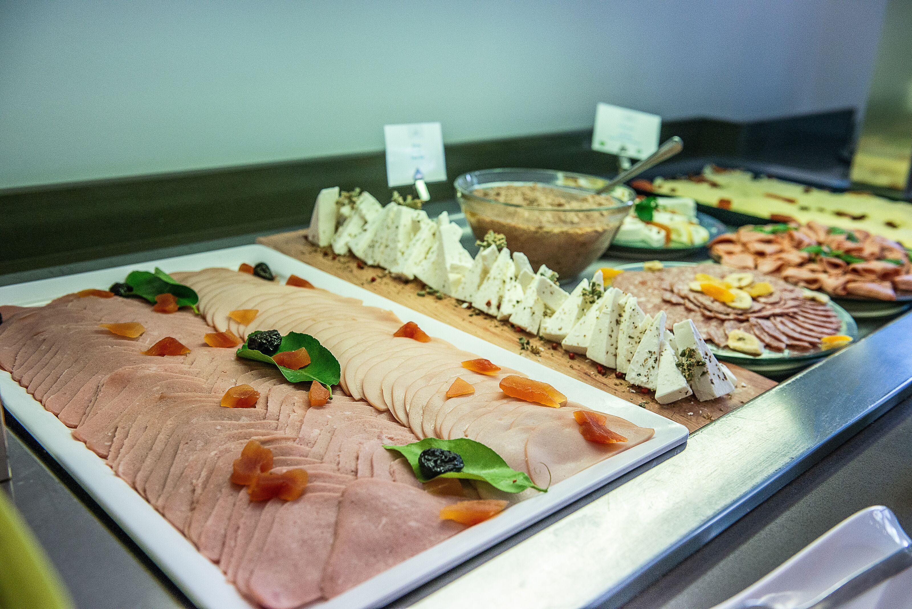 Buffet amb diferents plats, incloent carn tallada, formatges i un bol de sopa.