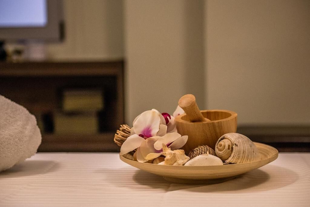 A wooden bowl with a wooden mallet, surrounded by dried flowers and shells on a table.