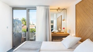 Habitación de hotel con cama, escritorio, silla, espejo y vistas al exterior.