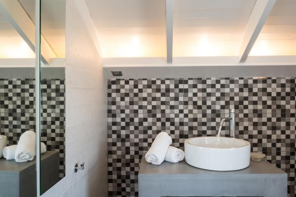 Un baño moderno con salpicadero de azulejos a cuadros, un lavabo redondo y un espejo.