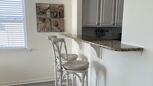 A kitchen with a granite countertop, white cabinets, and a window with blinds. - Large 4 bedroom penthouse unit 5 miles from Bethany Beach (Ocean View)