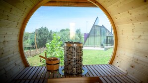 A wooden room with a circular window, a wooden bucket, and a metal container with rocks. - 3 Hills Boutique Hotel (Katerini)