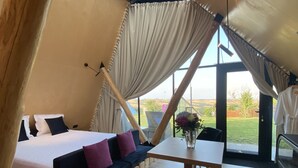 A cozy bedroom with a bed, a sofa, a table with a vase of flowers, and a view of the outdoors. - 3 Hills Boutique Hotel (Katerini)
