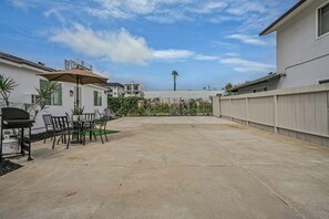 Un jardin avec un barbecue, du mobilier de jardin et une vue sur les maisons voisines.