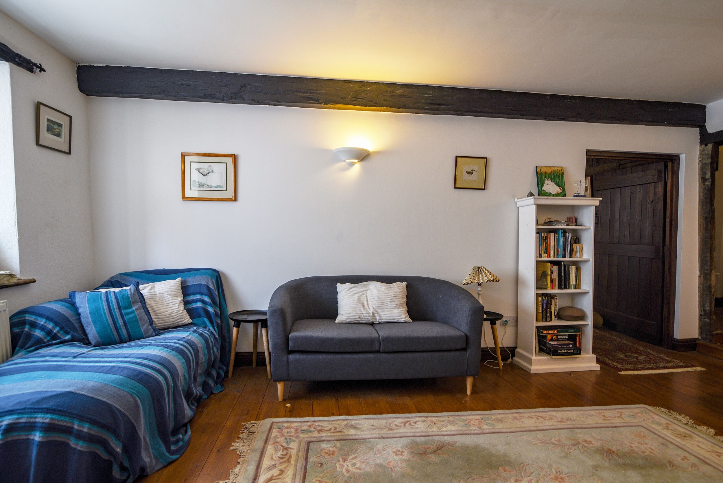 A cozy living room with a sofa, a small table, a bookshelf, and a fireplace.