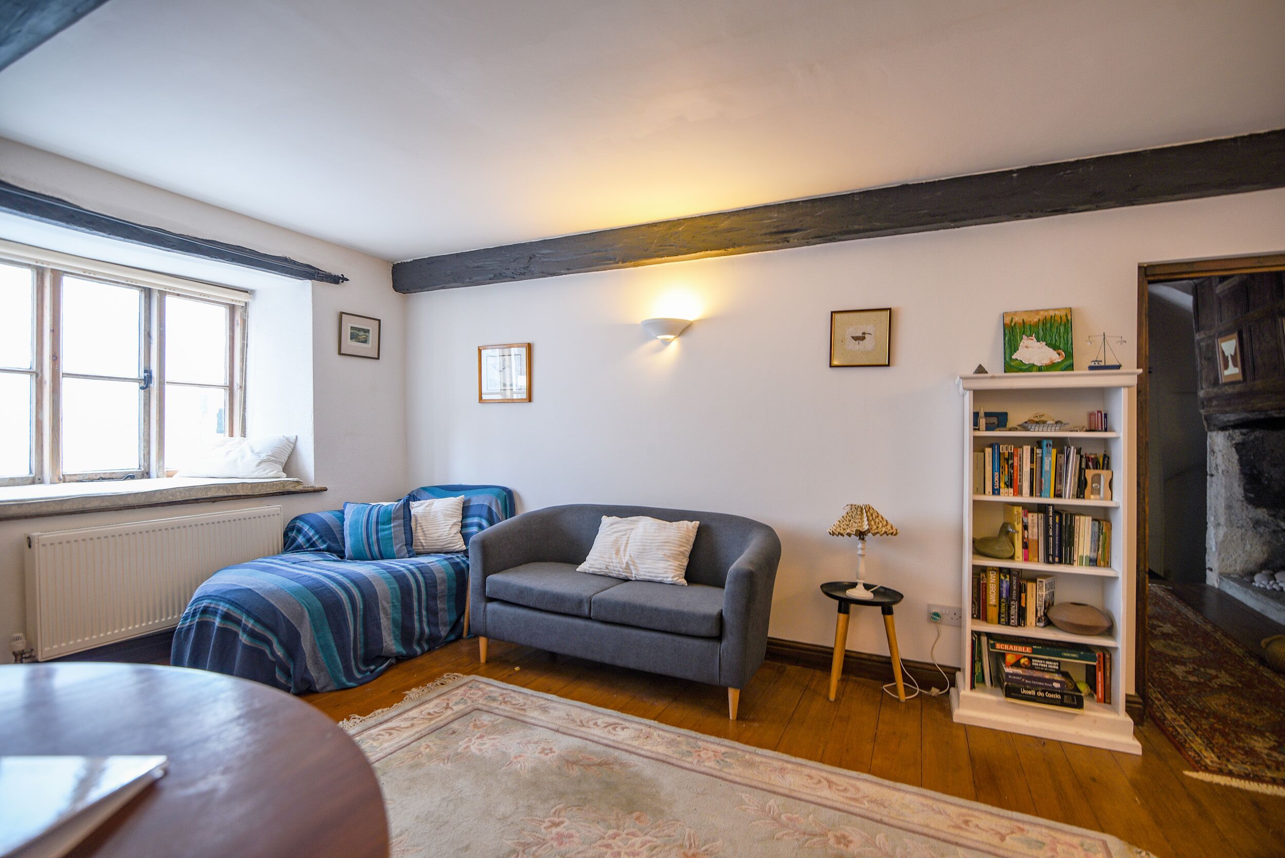A cozy living room with a sofa, a bookshelf, a fireplace, and a window.