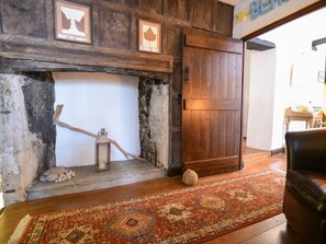 A rustic interior with a wooden door, a fireplace with a lantern, and a patterned rug. - Apt 1 44/45 Coombe Street (Lyme Regis)