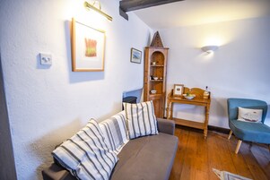 Una sala acogedora con un sofá, un aparador de madera, una mesita y un sillón azul.