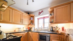 Una cocina con armarios de madera, estufa, microondas y cafetera.