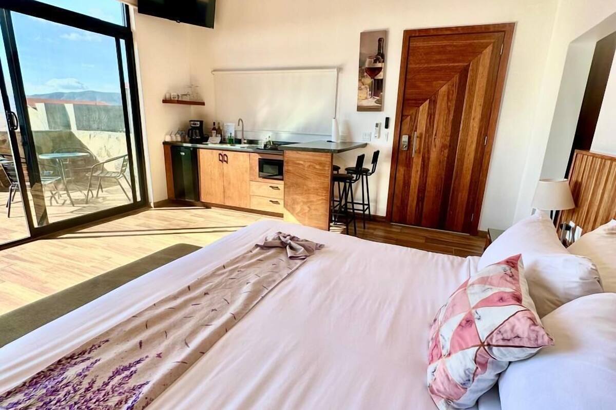 A bedroom with a large bed, a desk, and a view of the outdoors.