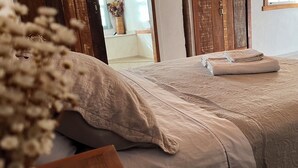 A bedroom with a bed, wooden doors, and a window. - Serra a vista chalés (Prados)