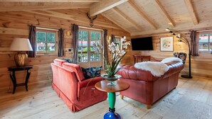 A wooden interior with a red sofa, a table with a vase, and a mounted deer head. - 'Chalet Kaisereck' with Terrace & Wi-Fi (Reit im Winkl)