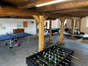 A room with a foosball table, ping pong table, and billiards table.