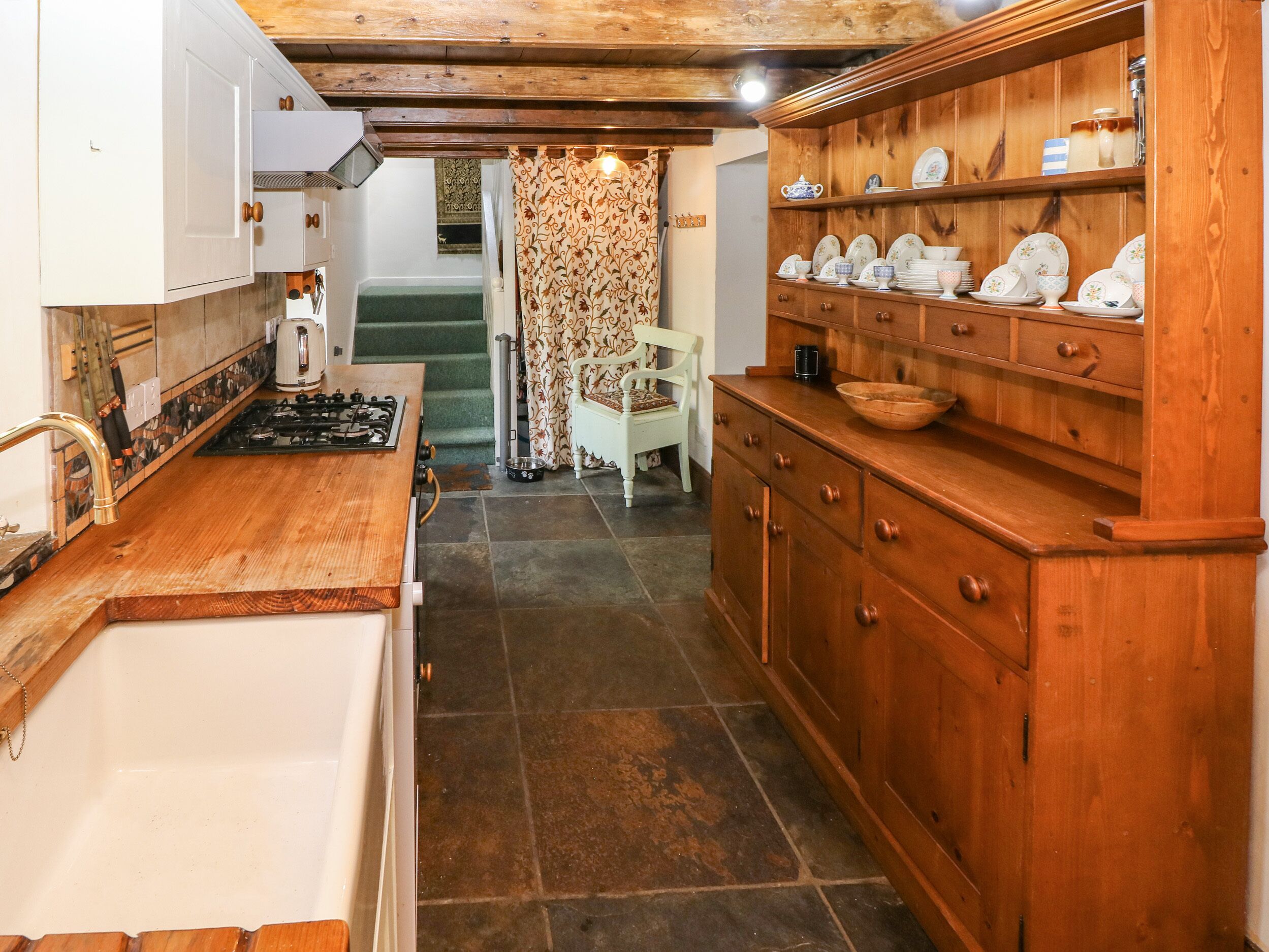 Una cocina con armarios de madera, una estufa y un comedor con una silla y una mesa.