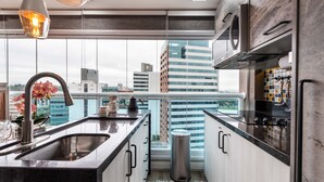 A modern kitchen with a large window, stainless steel appliances, and a view of the cityscape. - Summit Pinheiros by Okaeri Home Aparts (São Paulo)