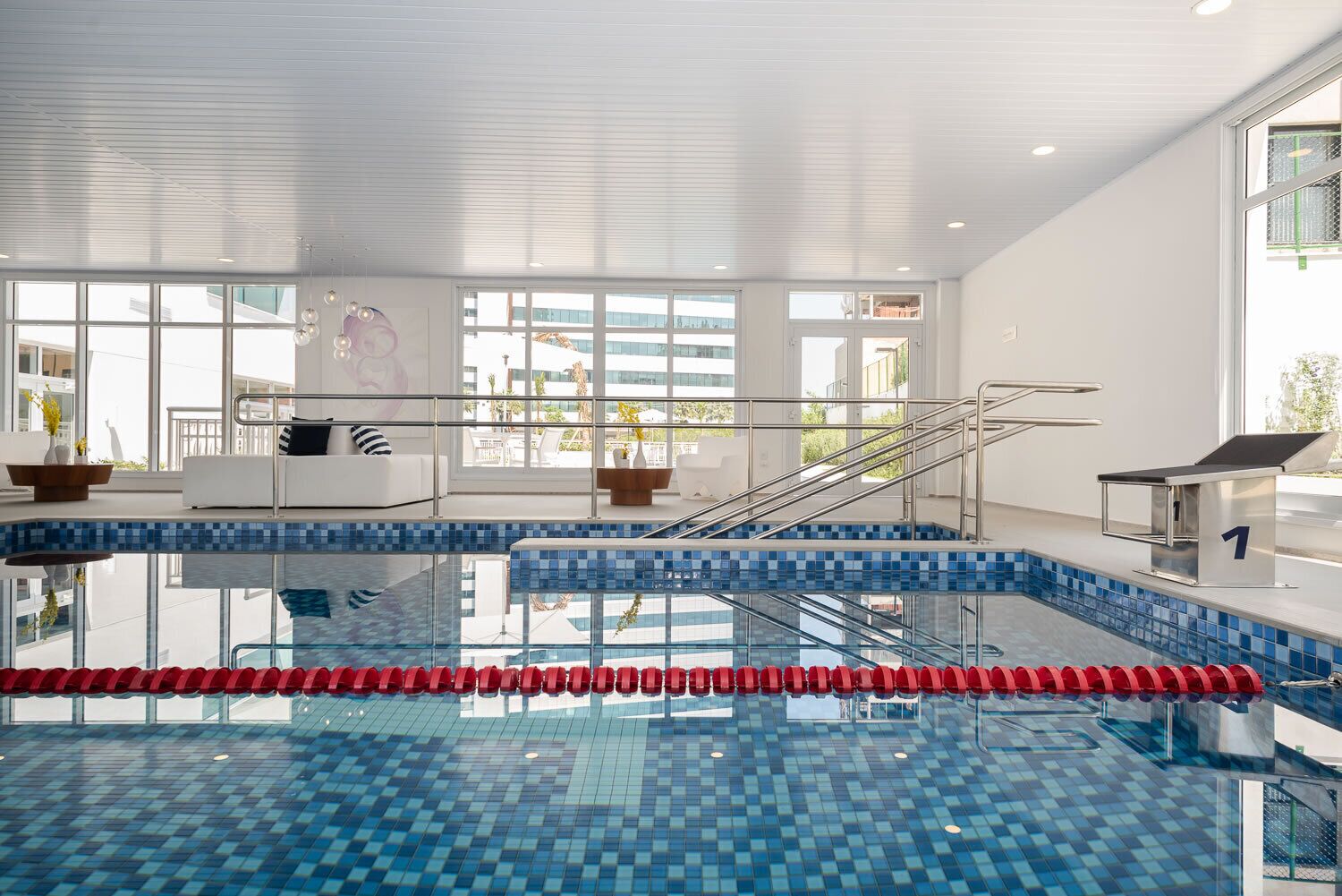 An indoor swimming pool with clear lanes, a lifeguard chair, and a staircase leading to the upper level.