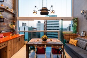 Una cocina moderna con comedor, ventanas amplias y vistas a la silueta urbana.