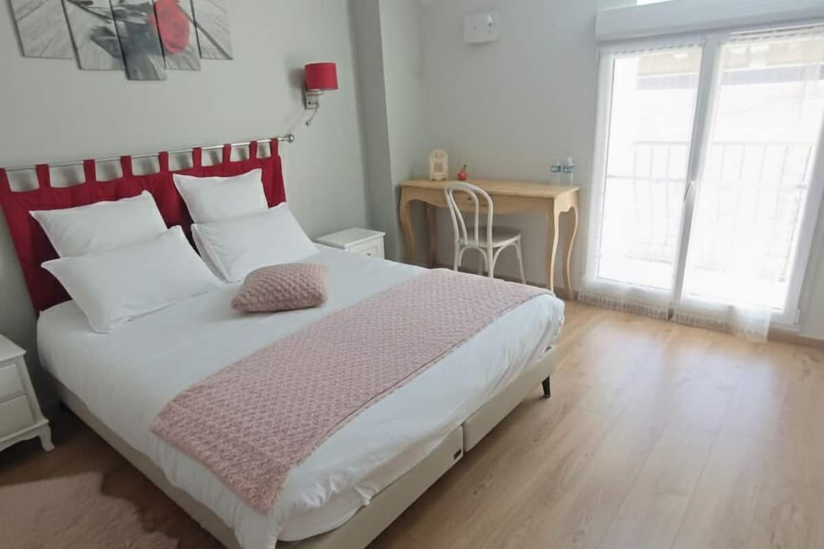 Een slaapkamer met een bed, nachtkastjes, een bureau en een stoel.