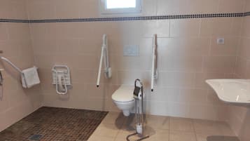 Een badkamer met een wit toilet, een witte wastafel en een douchegedeelte met betegelde vloer.