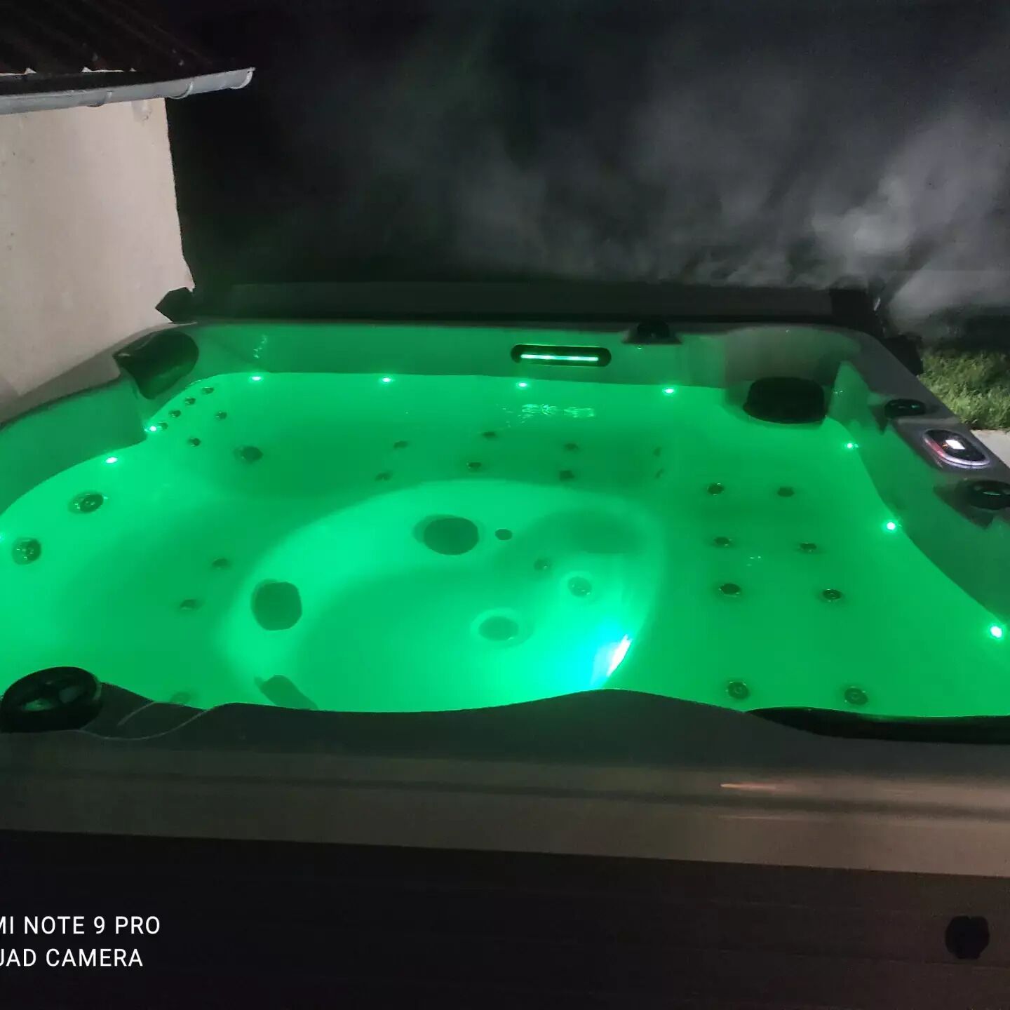 Een jacuzzi met groene verlichting en stoom.