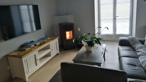 Un salon équipé d’un téléviseur à écran plat, d’un poêle à bois, d’un canapé et d’une table basse agrémentée d’une plante.