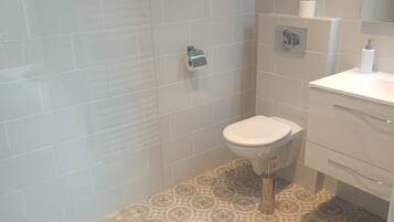 Ein Badezimmer mit Toilette, Waschbecken und Duschbereich.