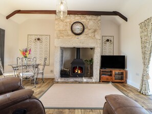A living room with a stone fireplace, a television, and leather sofas. - The Forge (Falmouth)