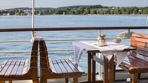 A wooden deck with a table and chairs overlooking a body of water.