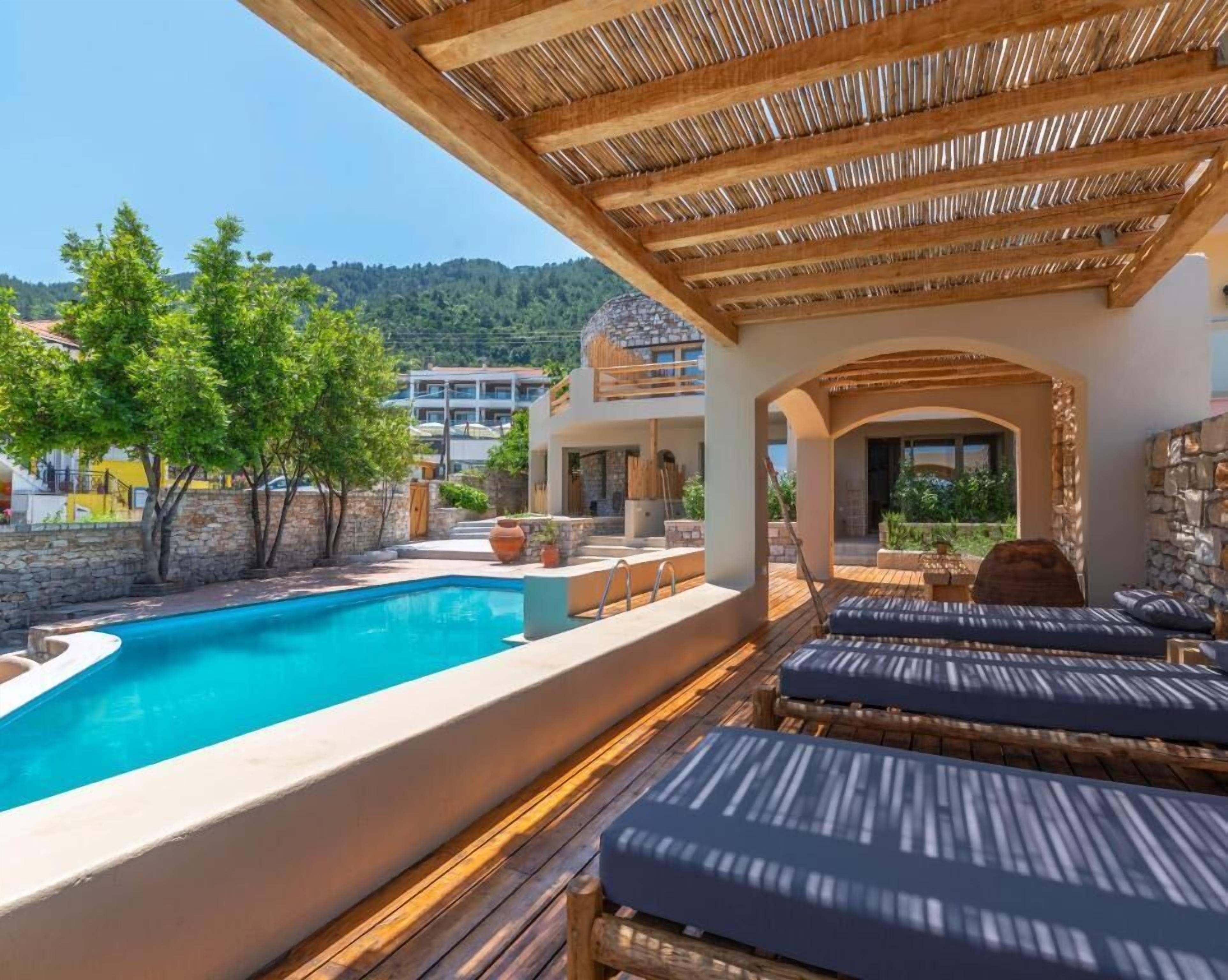 Un área junto a la piscina con sillones de descanso y una piscina.