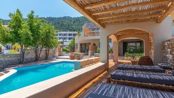Un área junto a la piscina con sillones de descanso y una piscina.