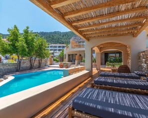 Una piscina al aire libre, sombrillas, sillones reclinables de piscina