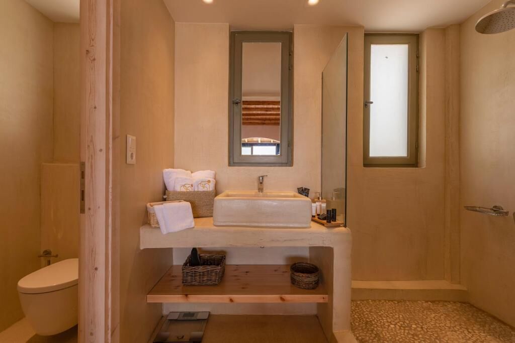 Un baño con tocador de madera, un lavamanos, un espejo y una zona de ducha.