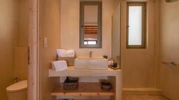 Un baño con tocador de madera, un lavamanos, un espejo y una zona de ducha.