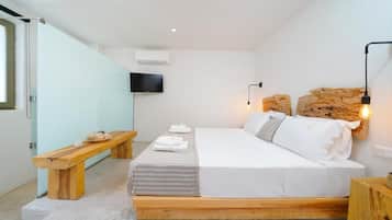Un dormitorio moderno con una cama de madera, un banco, un televisor de pantalla plana y una pared de acento de piedra.