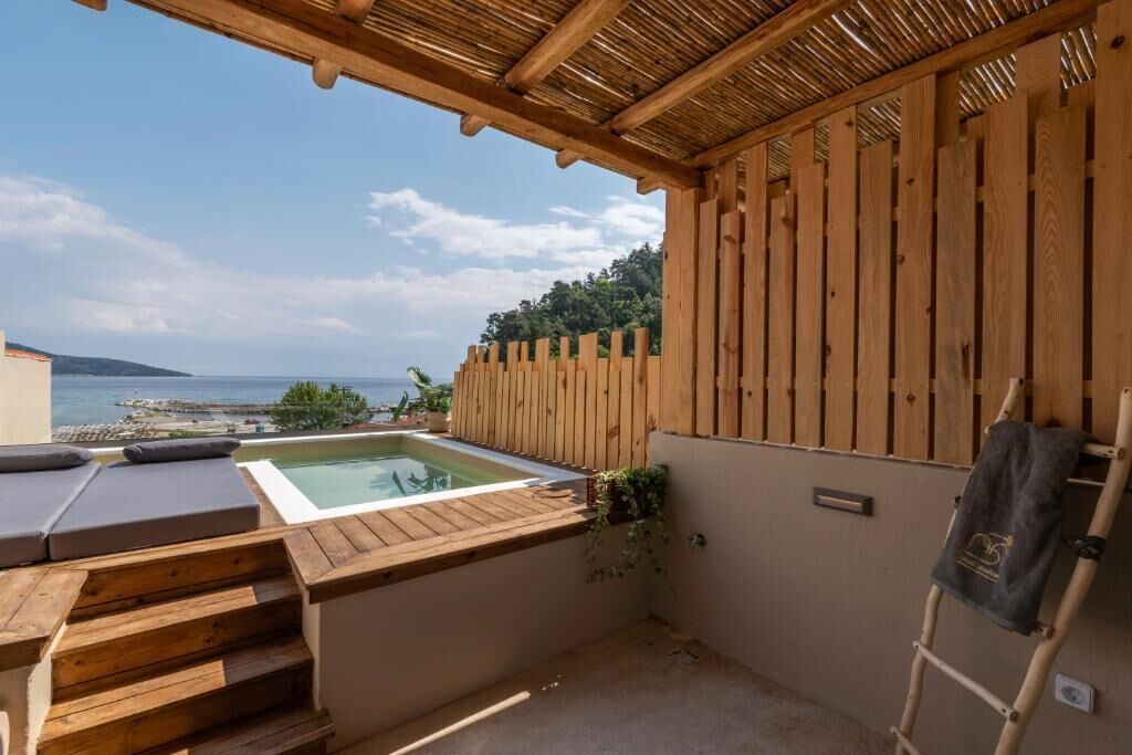 A wooden deck with a hot tub, steps leading to a pool, and a view of the sea.
