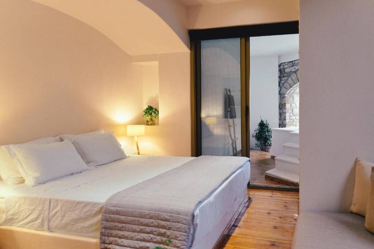 Un dormitorio con cama, lámpara de noche y vista a una escalera de piedra que da a un espacio exterior.