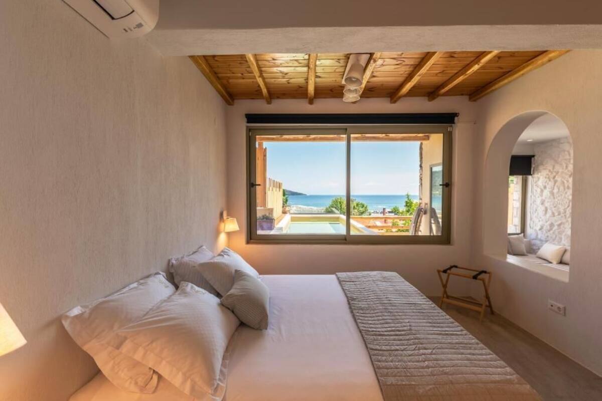 Un dormitorio con una cama grande, una ventana con vista al mar y un techo de madera.