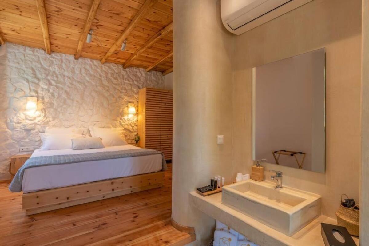 Un dormitorio con cama de madera, pared de piedra y un espejo grande sobre un lavamanos.