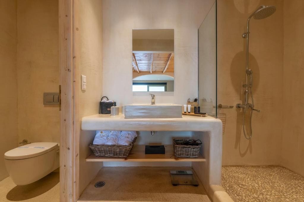 Een moderne badkamer met een houten wastafelmeubel, een grote spiegel, een douche en een toilet.