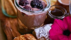 Um prato de sobremesas com doces variados e um copo de mousse de chocolate coberto com frutas vermelhas.